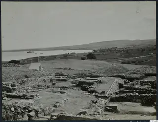 Excavated stone wall foundations at Soli, with a canvas tent on the left and the sea and boats beyond