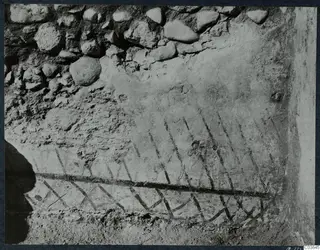 Room X at Soli, Cholades: painted diagonal lines on a plastered wall, with rough stone masonry above
