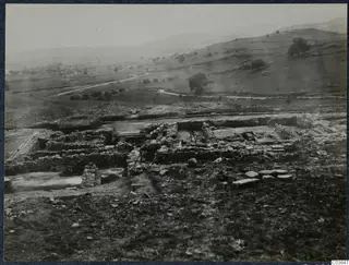 Excavated stone walls and foundations at Soli, Cholades, with fields, hills and a winding road beyond