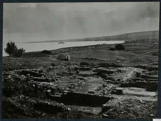 Excavation at Cholades, Soli, Temples A-B, with wall foundations, a tent and a boat on the water
