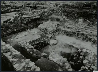 Excavated stone walls and foundations at Soli, Cholades temples, with a standing man by a bench at the top right