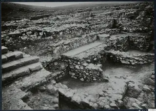 Excavated stone walls and a flight of cut stone steps at Soli, with the ruins of the Cholades temples across the site.