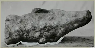 Fragment of a marble sculpture, a weathered stone form with a rounded end and a small raised projection on top.
