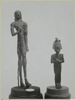 Two small bronze figures on wooden bases: a standing male figure at left and a smaller figure in a tall headdress at right.