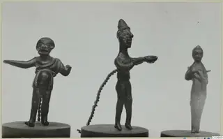 Three small bronze figurines standing on round wooden bases.