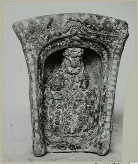 Terracotta object with a relief figure standing in an arched niche, photographed from the front.