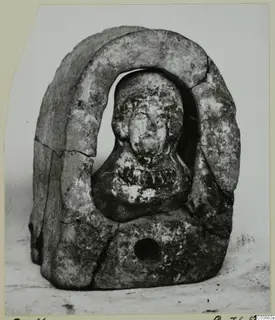 Terracotta figurine of a head and shoulders set within a curved arch-shaped frame, broken at the edges