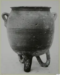 Pottery vessel with two loop handles and three tubular legs, decorated with dark painted bands and concentric circles.