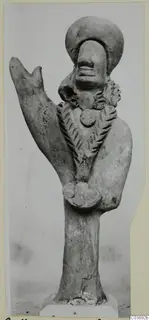 Terracotta figurine with a large rounded head, an incised pattern across the chest and a raised projection on one side