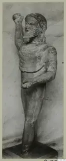 Limestone statue of a bearded standing male figure from Kition, one fist raised beside the head