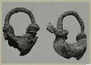 Two corroded metal objects with arched loops, from Vouni T. 1-16