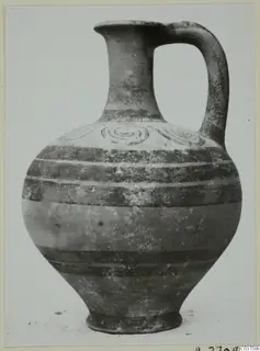 Pottery jug with a single loop handle, a spiral-decorated shoulder and dark painted bands, photographed against a plain background.