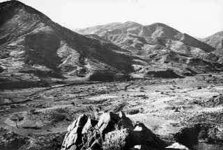 View over the Kambos valley at Soli, with hills rising on the left and right and rocks in the foreground.