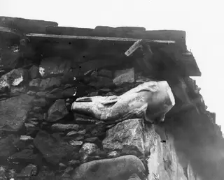 Aphrodite statue fragment in situ at Galini, lying on a stone wall beneath a wooden beam