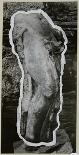 Marble sculpture fragment of a headless standing figure on a stone base, against a stone wall