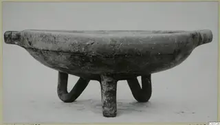 Pottery White Painted III-1 bowl on three tubular legs, with a small horizontal lug at each side of the rim.