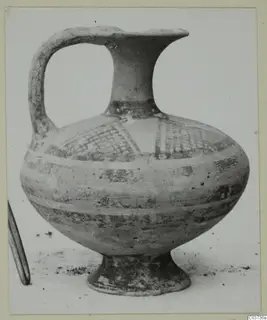 White Painted I jug with a strap handle, cross-hatched panel and painted bands, standing on a pale surface.