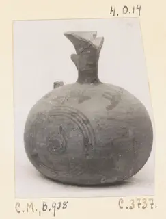 Round painted pottery vessel with a flared spout and dark concentric circle motifs, shown on a photo mount with handwritten labels