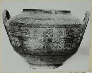 Two-handled Bichrome IV jug with painted bands of rings and cross-hatched panels, photographed against a pale background
