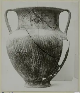Two-handled jar with painted bands and combed or striated body, shown on a plain background, broken and repaired along cracks.