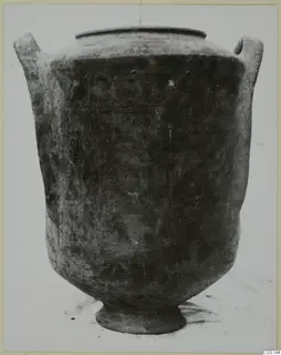 Pottery amphora with two handles and a ring foot, photographed alone against a pale background.
