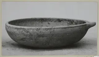 Pottery Plain White IV-V bowl with a single small horizontal handle, seen from the side
