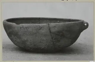 Plain bowl with a small pierced lug handle on one side, shown in side view against a pale background.