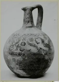 Globular jug with a tall neck, single loop handle and dark painted bands and concentric circles on a pale surface.