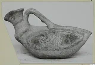 Bird-shaped pottery vessel with a strap handle arching over its back and a spout-like head at the left