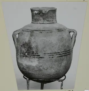 Globular two-handled pot with a short neck and dark painted horizontal bands, shown on a metal stand