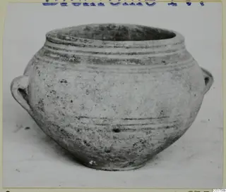Round-bodied pot with a wide open mouth and two small handles, photographed on a pale surface