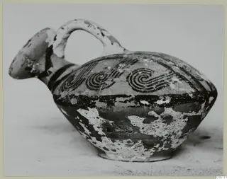 Pottery White Painted VI vessel with a beaked spout, strap handle and black spiral decoration