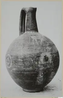 Round jug with a tall neck, strap handle, and pale painted concentric circles and a figure on its body