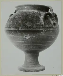 Pottery vessel on a tall ringed stem foot, with concentric circle motifs and a head-shaped handle attachment