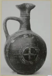 Round-bodied jug with a strap handle and flared spout, decorated with concentric rings and a cross-in-circle motif.