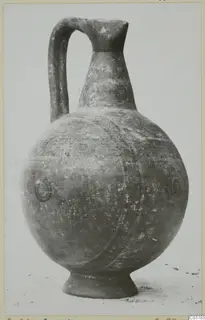Painted pottery jug with a tall neck, strap handle and round body, standing on a ring foot