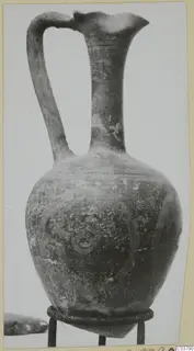 Jug with a flaring mouth and strap handle, standing on a metal ring stand
