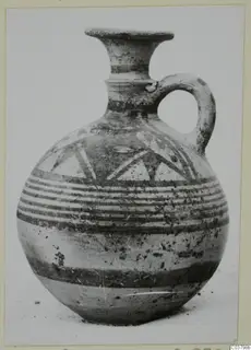 Pottery Bichrome IV jug with a flared rim, single handle, and painted bands and triangles