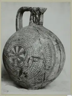 Round-bodied jug with a strap handle and painted concentric bands and a radiating rosette, photographed against a plain background.