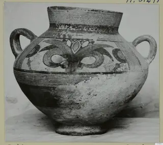 Two-handled painted pottery jug with a tall flaring neck and bands of linear and spiral decoration.
