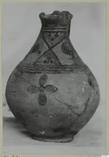 Painted pottery jug with a lipped mouth, dark banded decoration and a four-petalled motif on the body
