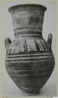 Tall two-handled painted pottery jar with a flaring neck, photographed upright against a pale background.