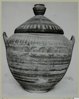 Lidded jar with concentric circle bands and hatched decoration, photographed upright against a plain background.
