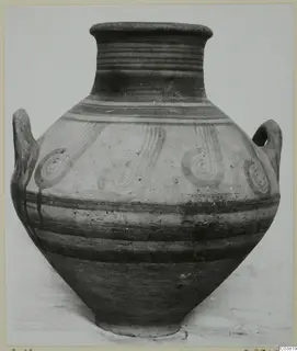 Two-handled painted jar with a flared rim, dark bands and dark spiral motifs on a pale ground, against a plain backdrop.