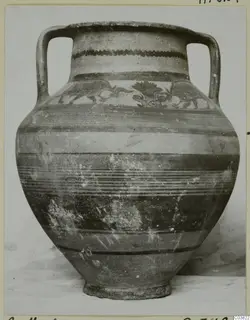 Two-handled painted pottery vessel with horizontal bands and a painted motif band on the shoulder, photographed on a card mount.