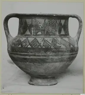 Two-handled pottery jar with a footed base and painted geometric bands, photographed against a plain background.
