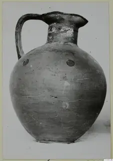 Pottery jug with a single strap handle, a tall neck and concentric circle motifs on the rounded body