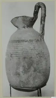 Pottery jug with a tall strap handle and dark painted horizontal bands on the body