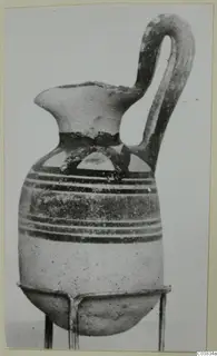Pottery Bichrome I vessel with one loop handle and dark painted bands, shown on a wire stand