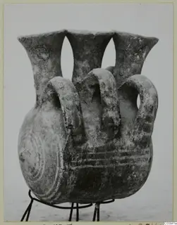 Three-necked vessel with looped handles on a wire stand, with concentric circle decoration on the side
